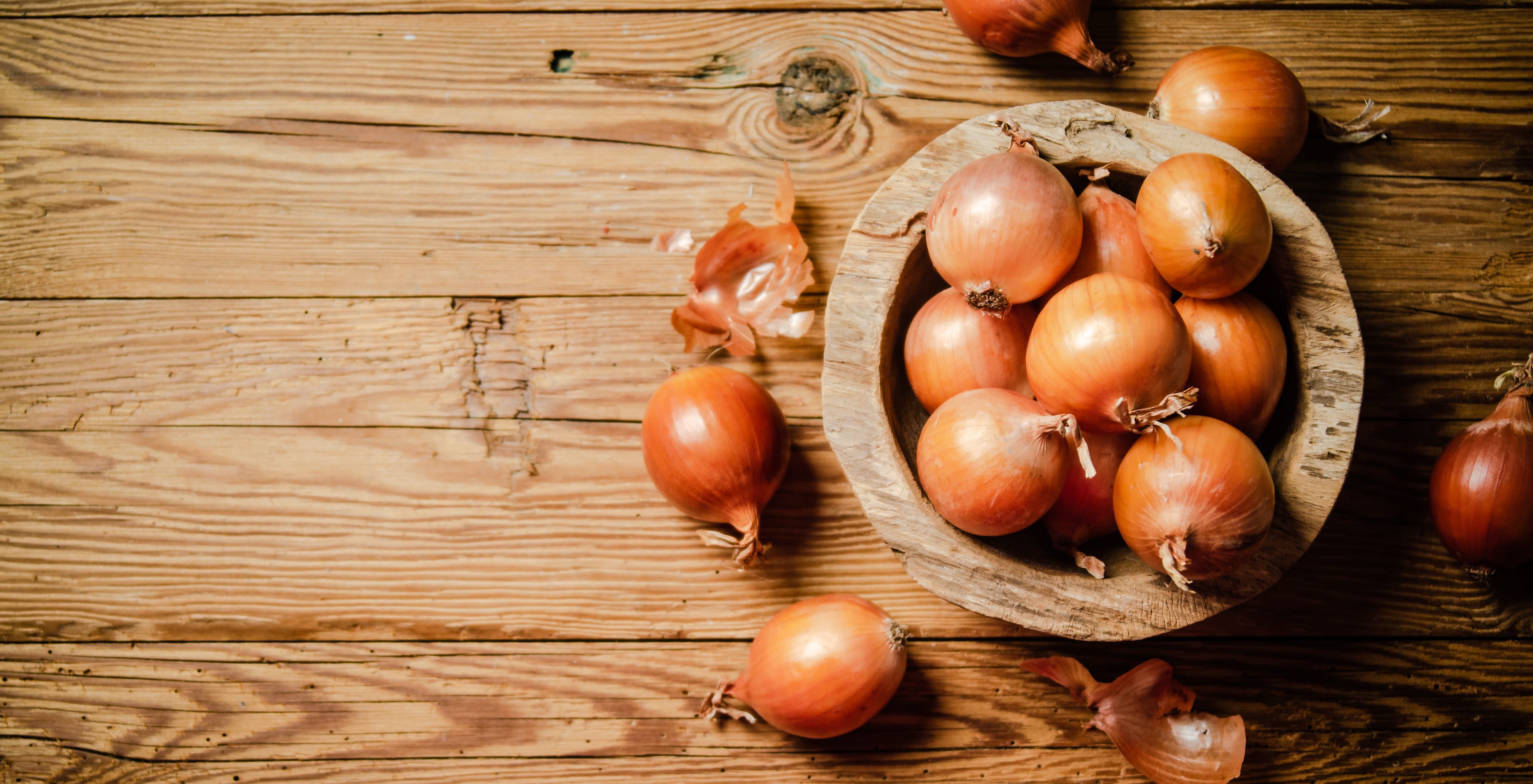 Golden onions in a wooden bowl